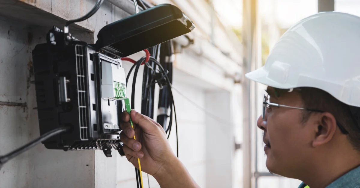 What You Can Expect During a Fiber Internet Installation 2 A fiber engineer working outside on the home's connection hub, installing fiber cables. He wears a helmet.